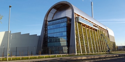 photograph of the Recycling and Energy Recovery Facility at Leeds, a glass and metal building with green foliage on the outer side walls