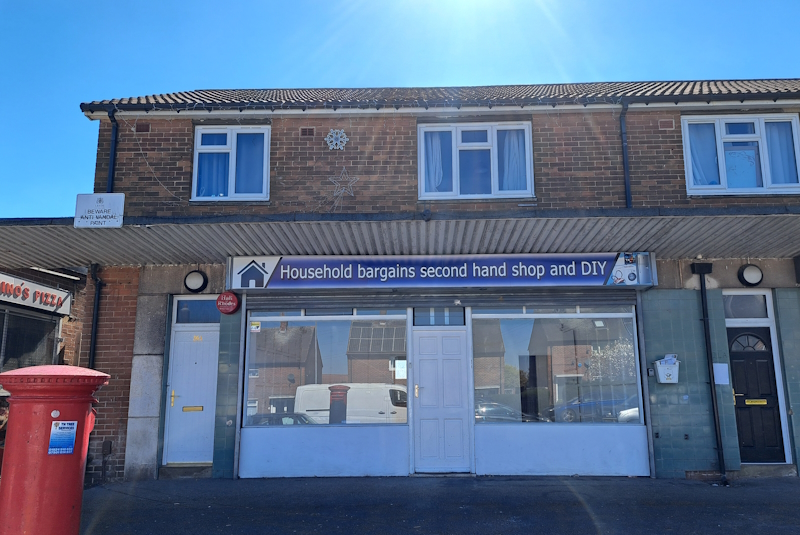 Exterior of two storey building with shop downstairs, bright blue sky above