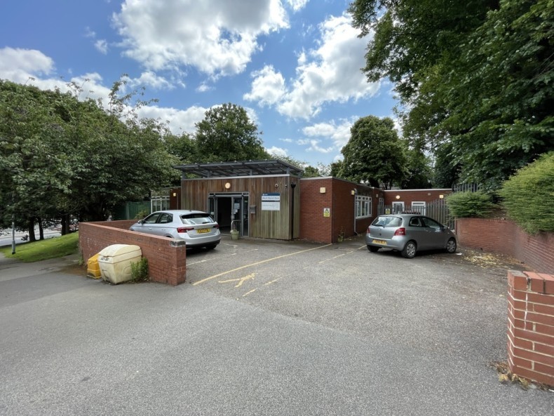 One-storey building with car park, surrounded by trees