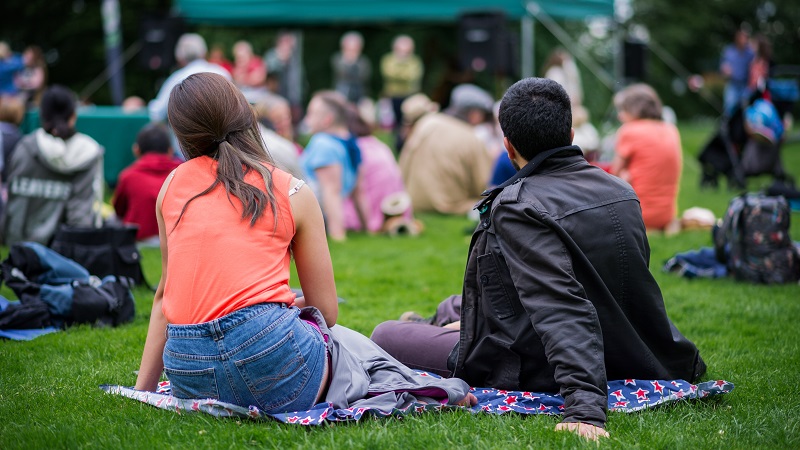 Two people sat in a crowd at an event on grass