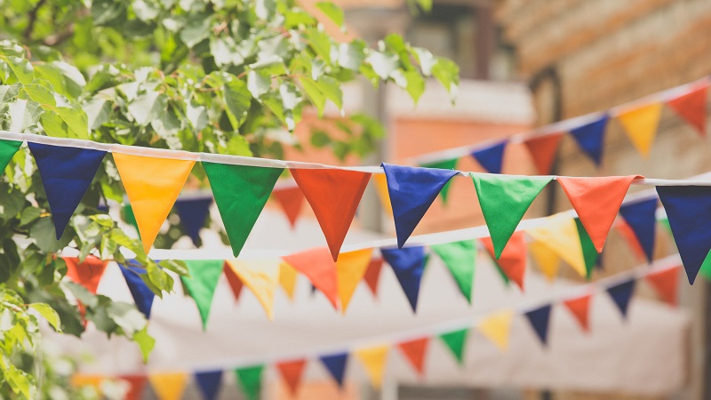 colourful bunting with trees and a building in the backdrop