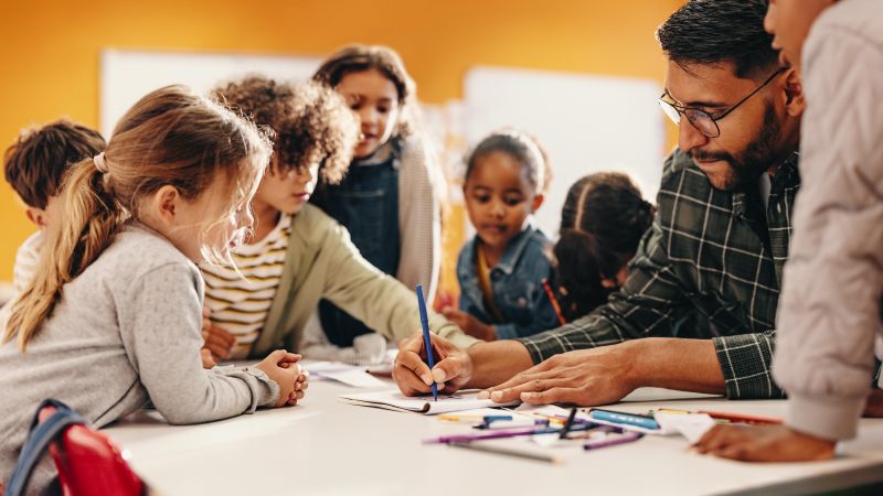 teacher showing children work around a small table
