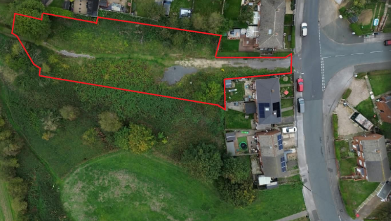 An aerial view of Manor road, with a red outline on a piece of land for sale