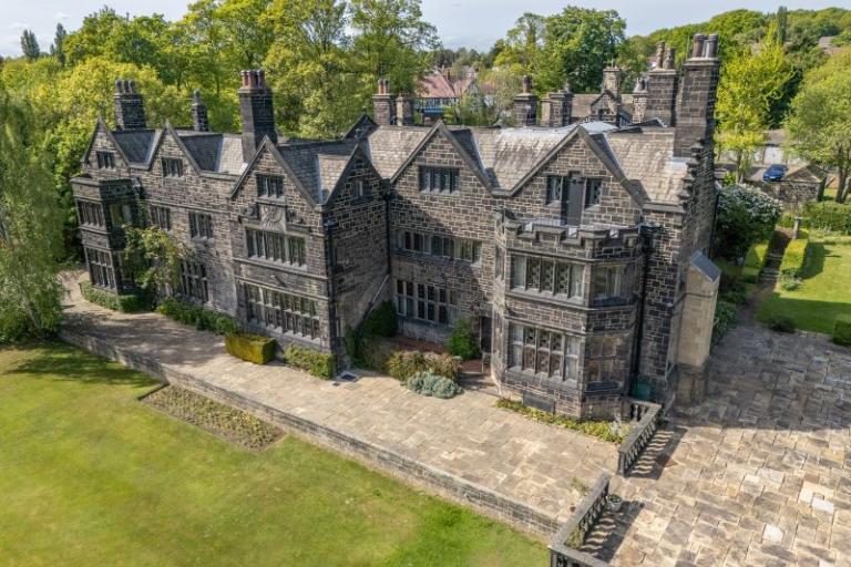 Photograph of the main stone building set in leafy surrounds