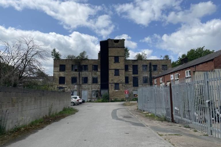 Photo of St Ann's Mills showing derelict 3 storey building with tower feature and yard area to front