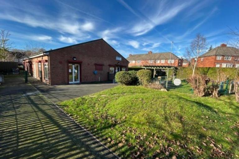 Brown building under blue sky atop a grass verge