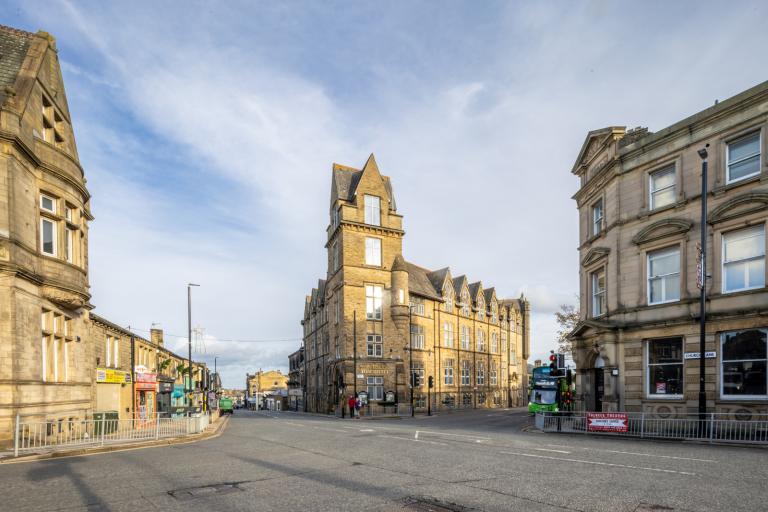 View of Pudsey town hall, a large Victorian structure on the corner of a crossroads with shops opposite