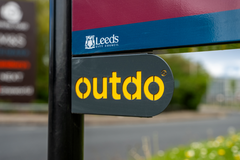 Image shows an arrow direction sign bearing the Outdo logo 